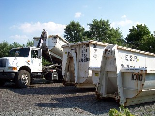 Three white rental dumpsters and a truck