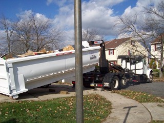 Truck dropping off a white rental dumpster