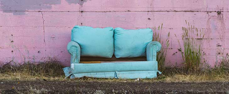 Old, broken, blue couch by curb